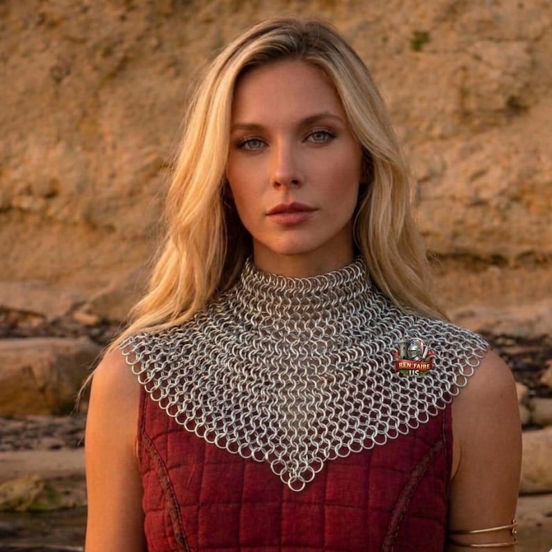 May include: A silver chainmail collar with a high neck, worn over a burgundy vest. The chainmail is made of small, interlocking metal rings. The vest is quilted. The Ben Faire LLC logo is visible on the right side of the collar.