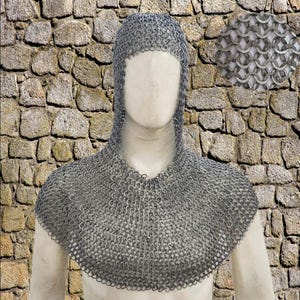 May include: A silver chainmail coif, a hood and shoulder covering made of interlocking metal rings. The coif is displayed on a mannequin against a stone wall background. A close-up inset shows the chainmail weave.
