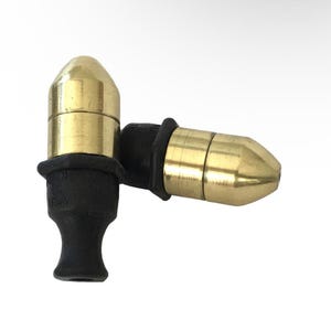 May include: Two brass smoking pipes with black stems are displayed against a white background. The pipes have a cylindrical design with a conical tip. The brass has a polished, shiny finish.