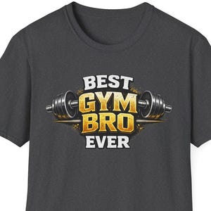 Puede incluir: Camiseta gris oscuro con el texto "BEST GYM BRO EVER" en dorado y blanco, con un gráfico de barra. La camiseta es de cuello redondo y parece estar hecha de un material suave.