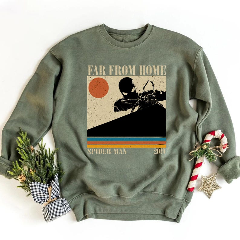 May include: Sage green sweatshirt with a Spider-Man graphic, the text "FAR FROM HOME", and "SPIDER-MAN 2019". The design has a retro style with a sun and coloured stripes.