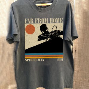 May include: Dark grey t-shirt with a graphic from the film "Spider-Man: Far From Home." The design features a silhouette of Spider-Man, a red sun, and the text "SPIDER-MAN 2019" in a retro style.