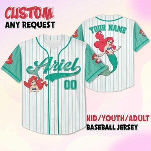May include: White baseball jersey with green pinstripes and sleeves. Features the name "Ariel" in green script on the front, along with the number "00". The jersey includes an illustration of Ariel from The Little Mermaid. The back of the jersey says "YOUR NAME".