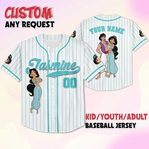 Puede incluir: Camiseta de b&eacute;isbol blanca con finas rayas y detalles turquesa. La parte delantera muestra el nombre "Jasmine" y el n&uacute;mero "00". La parte trasera tiene un gr&aacute;fico de Aladdin y Jasmine, con el texto "YOUR NAME". Disponible en tallas para ni&ntilde;os, j&oacute;venes y adultos.