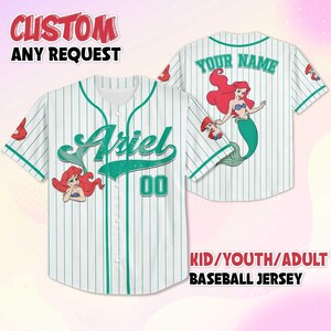 May include: White baseball jersey with green pinstripes, featuring the name "Ariel" in green script on the front. The jersey has a cartoon image of Ariel and the number "00". The back of the jersey has the text "YOUR NAME" and another Ariel graphic. The text "CUSTOM ANY REQUEST" and "KID/YOUTH/ADULT BASEBALL JERSEY" are also visible.