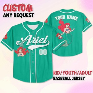 May include: Teal baseball jersey with white trim and buttons. The front features the name "Ariel" in white script, the number "00", and an illustration of Ariel. The back displays Ariel and the text "YOUR NAME". The text "CUSTOM ANY REQUEST" is at the top.
