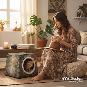 以下が含まれることがあります： 丸い開口部のある花柄の猫用ハウスの中に猫がいます。近くに座っている女性は、カップと帽子を持っています。シーンには、コーヒーテーブル、植物、窓が含まれています。