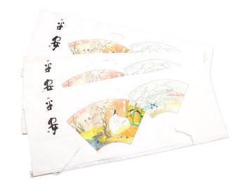 Puede incluir: Abanicos de papel blanco con caligrafía japonesa e ilustraciones coloridas. Los abanicos presentan imágenes de paisajes, pájaros y diseños florales en tonos naranja, amarillo, verde y azul. La caligrafía es en tinta negra.