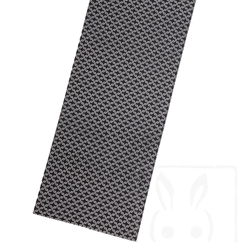 May include: Black fabric with a white repeating pattern of a stylized S shape.
