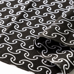 May include: Black fabric with a white wave pattern. The fabric is folded over on itself, showing the pattern on both sides.