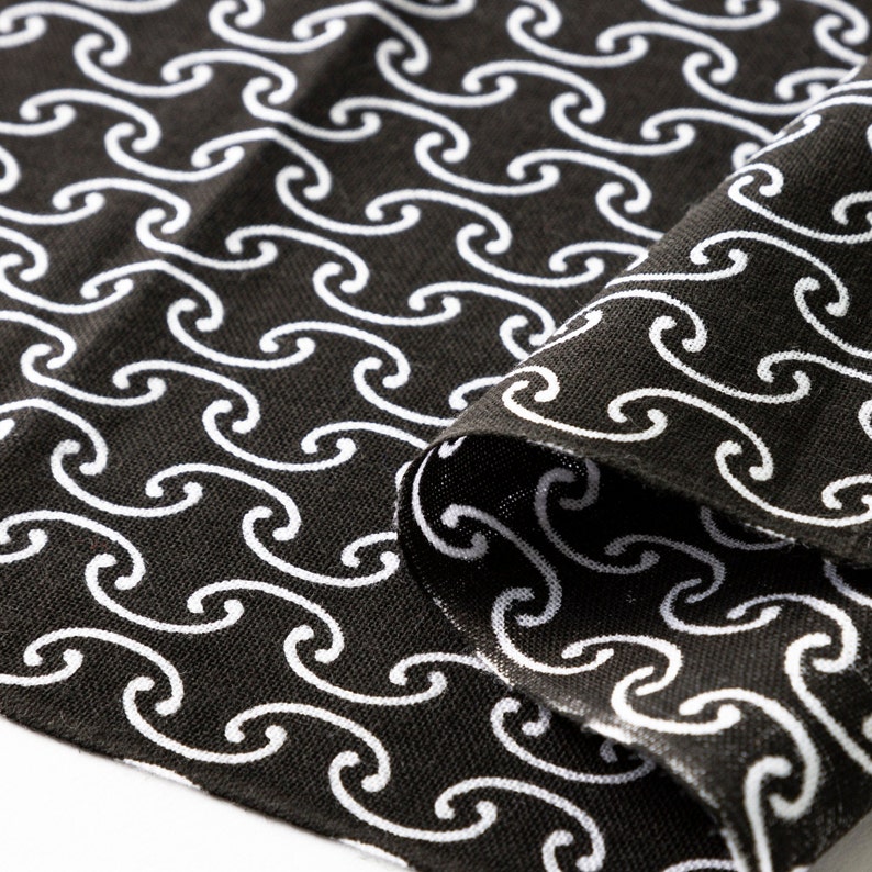 May include: Black fabric with a white wave pattern. The fabric is folded over on itself, showing the pattern on both sides.