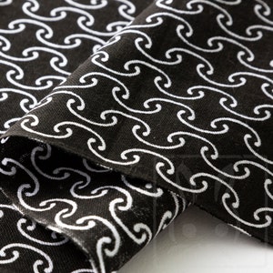 May include: Black fabric with a white wave pattern. The fabric is folded in half, showing the pattern on both sides.