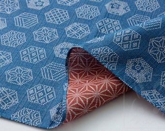 May include: A blue fabric with a white geometric pattern on one side and a red fabric with a white geometric pattern on the other side. The fabric is folded in half, showing both sides.