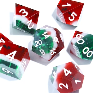 May include: A collection of polyhedral dice in red, white, and green. The dice have white numbers and a marbled appearance. The set includes various shapes, such as six-sided and twenty-sided dice, suitable for tabletop games.