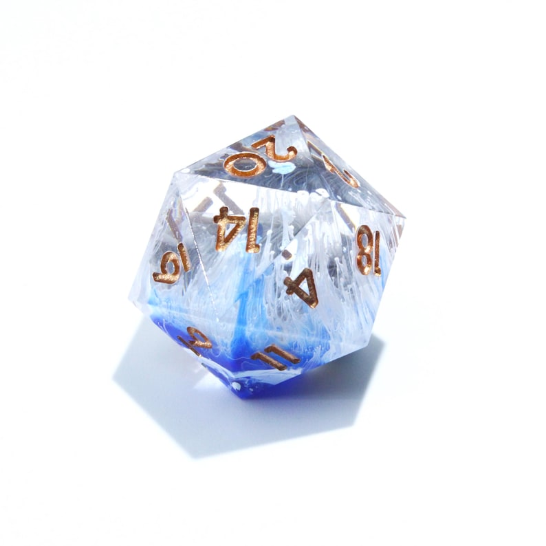 May include: A clear, twenty-sided die with blue and white internal marbling. The numbers are in a copper color. The die is designed for tabletop role-playing games.