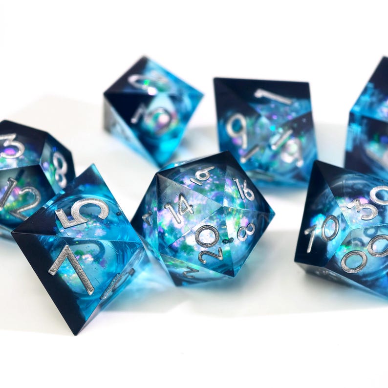 May include: A set of polyhedral dice with a blue and black design. The dice have silver numbering and a shimmering, galaxy-like interior. The dice are made of a clear resin material and are designed for tabletop gaming.
