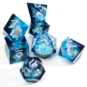 May include: A set of seven polyhedral dice in various shapes. The dice are transparent blue with silver numbering and iridescent glitter inclusions. Ideal for tabletop gaming.