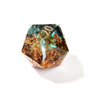 Op de afbeelding: Een twintigzijdige polyhedrale dobbelsteen met een uniek ontwerp. De dobbelsteen heeft een goud- en teal interieur met een wit waterval effect. De cijfers zijn koperkleurig. Geschikt voor tabletop rollenspellen.