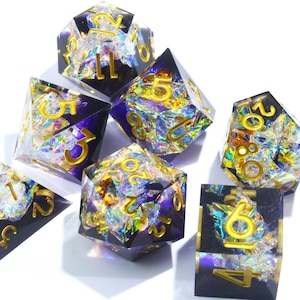 Könnte beinhalten: Sieben polyedrische Würfel mit dunkelvioletter Basis, goldfarbenen Zahlen und schillernden Glitzer-Einschlüssen. Die Würfel sind für Tabletop-Rollenspiele konzipiert und werden auf weißem Untergrund präsentiert.
