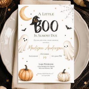 May include: A rectangular baby shower invitation card featuring a watercolor design with a crescent moon, a witch hat, two ghosts, a spider web, bats, and two pumpkins. The text reads A LITTLE BOO IS ALMOST DUE, honoring Madison Anderson, October 19.