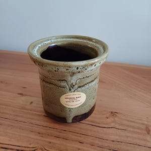 May include: A set of three ceramic mugs with a speckled, matte finish in cream, light grey, and dark grey. Each mug has a simple, modern design and a rounded handle.