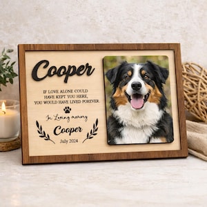 May include: A wooden pet memorial frame with a photo of a dog. The frame has the name "Cooper" in large, raised letters, and the text "In Loving Memory Cooper July 2024". The dog in the photo is black, brown, and white.