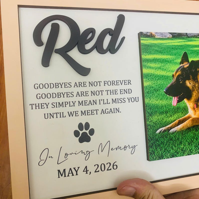 Puede incluir: Un marco de madera rectangular que contiene una placa conmemorativa con el nombre Red en letras negras en relieve. El texto dice: GOODBYES ARE NOT FOREVER GOODBYES ARE NOT THE END THEY SIMPLY MEAN I'LL MISS YOU UNTIL WE MEET AGAIN. Incluye una huella, In Loving Memory y MAY 4, 2026, junto a la foto de un perro pastor alem&aacute;n.