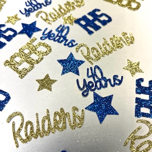 May include: A collection of glittery confetti pieces in blue and gold. The shapes include five-pointed stars and text cutouts reading 1985, 40 years, Raiders, and RHS. The pieces feature a textured, sparkling finish on the front surfaces.