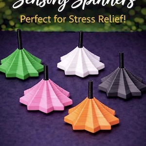 May include: Five colorful sensory spinners in green, white, pink, orange, and gray. Each spinner has a starburst design and a black stem. The text "Sensory Spinners" is at the top of the image.