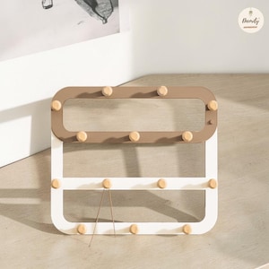 Puede incluir: Organizador de pared moderno de forma rectangular con esquinas redondeadas. La sección superior es marrón y la inferior blanca. Cuenta con clavijas de madera para colgar objetos. El diseño es minimalista y funcional, adecuado para la organización del hogar.