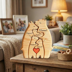 Peut inclure: Figurine en bois représentant une famille d'ours avec cinq ours, chacun avec un nom. L'ours central a un cœur rouge. Les noms sont écrits en cursive. La figurine est sur une table en bois avec des photos encadrées en arrière-plan.
