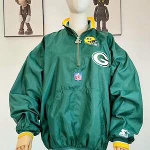 May include: Green and yellow NFL Green Bay Packers Starter jacket. The jacket features a half-zip closure, team logo, and NFL patch. The jacket has a yellow collar, cuffs, and hem. The jacket is displayed on a mannequin.