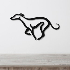 Black metal greyhound wall art with a minimalist silhouette design, mounted on a white wall above a light wood surface.