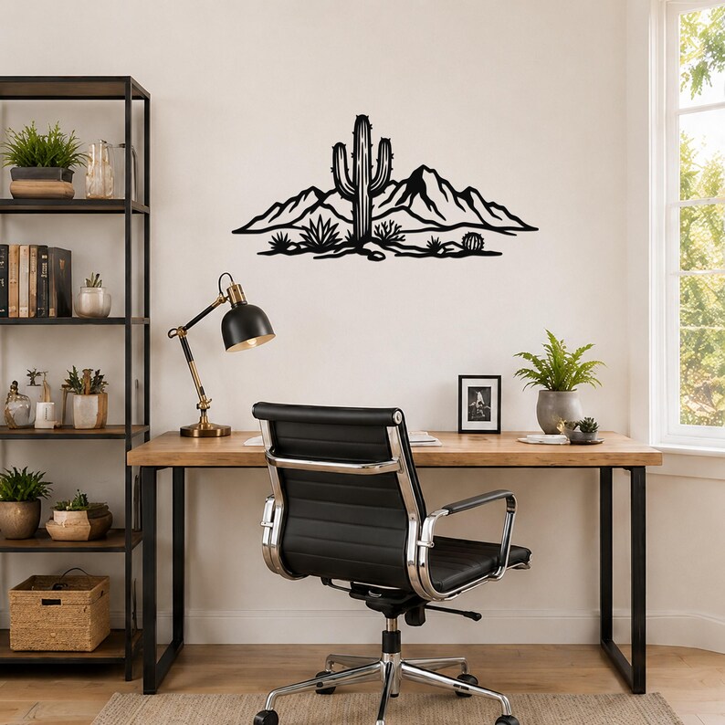 Black metal wall art featuring a saguaro cactus and desert mountain silhouette, mounted above a wooden desk in a home office.