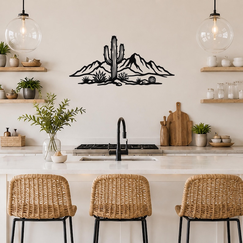Black metal wall art featuring a saguaro cactus and mountain silhouette, mounted above a kitchen counter with open shelving and pendant lights.