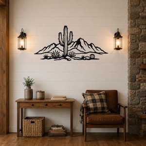 Black metal wall art silhouette of a saguaro cactus and desert mountains, mounted on a shiplap wall above a wooden console table in a living room.