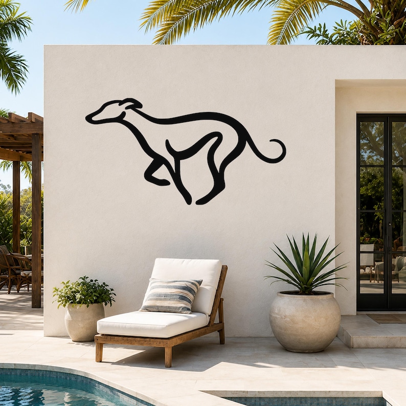 Black metal greyhound wall art silhouette mounted on an outdoor patio wall above a lounge chair, with palm trees and a pool in the background.