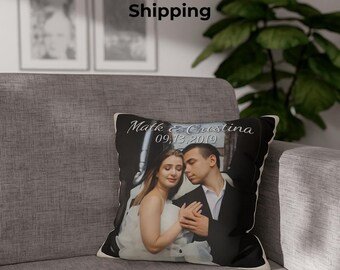 May include: A personalized 18x18 inch photo pillow featuring a couple embracing. The pillow displays the names "Mark & Cristina" and the date "09.13.2019". The pillow is placed on a gray sofa.