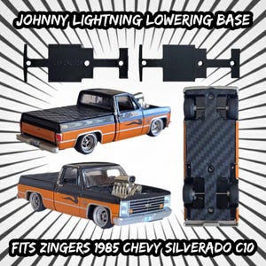 Peut inclure: L'image présente une base d'abaissement noire Johnny Lightning et deux modèles de camions. Les camions sont noirs et orange avec des détails argentés. Le texte indique "JOHNNY LIGHTNING LOWERING BASE" et "FITS ZINGERS 1985 CHEVY SILVERADO C10".