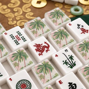 May include: A set of white mahjong tiles featuring a mix of traditional black and red character designs, a red dragon emblem, and tiles decorated with a tropical palm tree illustration against a soft pink and light green background.
