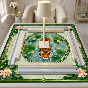 May include: A rectangular mahjong mat featuring a central circular illustration of a tiger swimming in a pond with green lily pads and pink lotus flowers. The mat includes four white tile racks and a white lamp stand in the center.