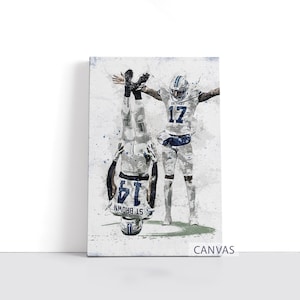 Op de afbeelding: Canvas print met twee American football spelers in witte en blauwe uniformen. Eén speler staat ondersteboven, de ander met uitgestrekte armen. Het canvas heeft een aquareleffect met blauwe verfspatten. De tekst "CANVAS" staat onderaan.