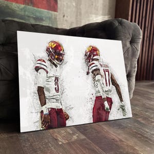 May include: A canvas print depicting two American football players in burgundy and white uniforms. The players are wearing helmets and are in action. The artwork has a sketched style with paint splatter effects.