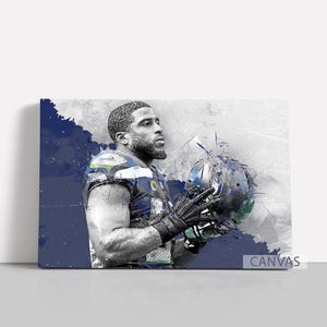 May include: Canvas print of a football player in a blue and green uniform, holding a helmet. The artwork has a watercolour effect with blue and grey tones. The word "CANVAS" is printed on the bottom right.