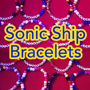 May include: A collection of circular beaded bracelets featuring colorful plastic beads and white letter beads spelling out names like Sonadow, Lansoni, Arthurlot, Shahrlina, Metashadow, Silvaze, Sonamy, Badget, Whispangle, Knuxouge, and Sonilver.