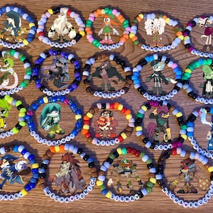 May include: A selection of colourful beaded bracelets, each showcasing a different cartoon character. The bracelets are made with various coloured beads and white letter beads spelling out character names. The characters are from a video game.