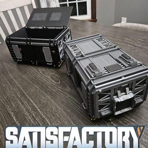 Puede incluir: Dos contenedores de almacenamiento futuristas detallados, uno negro y otro gris, con tapas con bisagras y diseños industriales. Los contenedores están sobre una superficie de madera. La palabra "SATISFACTORY" se muestra en plata y naranja.