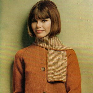 May include: A vintage-style ensemble featuring a rust-colored knit cardigan with two buttons, a matching skirt, and a patterned scarf. The outfit is a classic, retro look.