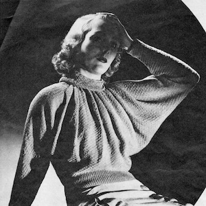 Könnte beinhalten: Schwarz-Weiß-Bild einer Person in einem strukturierten Strickpullover mit hohem Ausschnitt und langen Ärmeln. Der Pullover hat einen gerippten Saum und ein gerafftes Design an den Schultern. Die Person trägt auch Jeans.