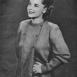 May include: A vintage black and white photograph of a woman wearing a knitted cardigan. The cardigan has a decorative trim and button closure. The woman is smiling and looking to the side.